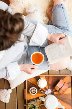 Top View Shot Of A Woman Reading A Book And Drinking Tea
