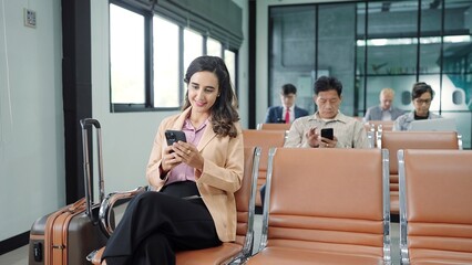 The passengers, tourist using smartphone while sitting on chair in terminal hall waiting flight in the departure gate at international airport. Travel concept