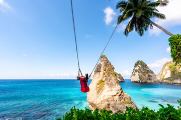 Wall Mural - Young woman tourist on Bali swing at Diamond beach at Nusa Penida island Bali, Indonesia