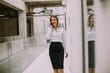 © BGStock72 - Young business woman using mobile phone in the office hallway