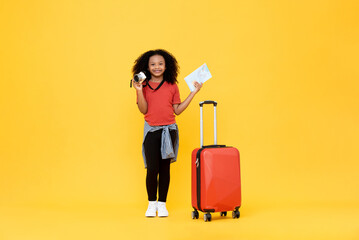 cute african american female kid with baggage holding camera and map in isolated yellow color backgr