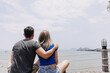 © Sevendeman - Couple of asian lover hug and hold sitting together looking out to the sea bay.