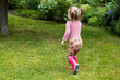 toddler girl spend time outdoor in rubber boots, children have fun in nature