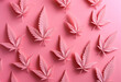 Overhead flat lay of pink marijuana cannabis leaves on a pink background
