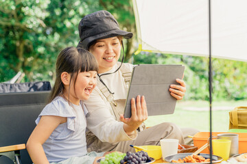 Canvas Print - キャンプ場でタブレットPCを使う親子（アニメ・映画・ワーケーション・ノマドワーク）
