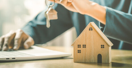 Wall Mural - Businessman choosing mini wood house model from model and row of coin money on wood table, selective focus, Planning to buy property. Choose what's the best. 