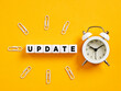 The word update on cubes with alarm clock and paper clips. Time for a software update. News update announcement.
