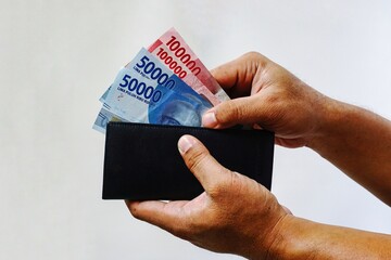 hands take rupiah money from wallet isolated on white background. 