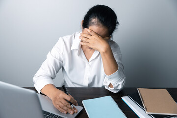 Wall Mural - A business office worker is an asian woman is sitting in front of the laptop computer. A businesswoman stressing her body part fingers, hands arm. A femaleOffice manager is exhausted at her workplace.