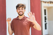 © luismolinero - Young Arabian handsome man holding home keys at outdoors saluting with hand with happy expression