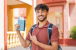 © luismolinero - Young Arabian handsome man holding a passport at outdoors and pointing it