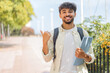 © luismolinero - Young student Arabian man at outdoors pointing to the side to present a product
