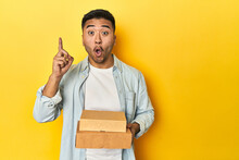 Asian Man Holding Delivery Food Boxes, Yellow Studio Backdrop Having Some Great Idea, Concept Of Creativity.