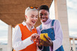 © Jose Calsina - Two happy women friends smiling and watching funny photos on a social media cellphone app. A pair of girls having fun buying together on a online shop with a smart phone. Ladies using a mobile phone