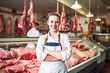Young woman standing in front of shelves with raw meat. Female butcher working in modern meathsop. Generative AI