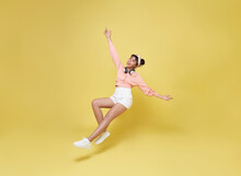 Happy Smiling Asian Girl Relaxing Floating In Mid-air Isolated On Yellow Background.