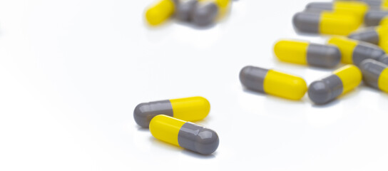 Wall Mural - Closeup yellow and gray capsule pills on white background. Prescription drugs. Pharmaceutical industry. Health and medical care concept. Pharmacy products. Capsule pills production manufacturing.