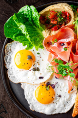 fried eggs with ham, salad and hummus