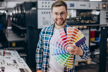 Man working in printing house with paper and paints