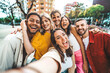 © Davide Angelini - Multicultural friends taking selfie pic with cellphone outside - Happy young people having fun hanging out on city street - Summer vacation concept with guys and girls enjoying summertime holiday