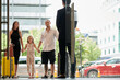 © DragonImages - Happy family of three standing at hotel entrance doors