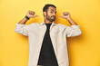 © Asier - Casual young Latino man against a vibrant yellow studio background, feels proud and self confident, example to follow.