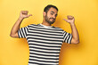 Casual young Latino man against a vibrant yellow studio background, feels proud and self confident, example to follow.
