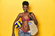 © Asier - African woman in bikini with beach bag and volleyball.