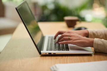 Hands of student working on laptop at her desk in home office