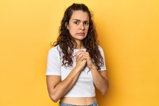 Young Caucasian woman, yellow studio background, scared and afraid.