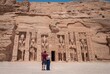 Young couple embraced, on their backs, enjoying the temple of Abu Simbel on her trip through Egypt. Temple of Queen Nefertari.