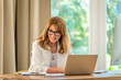 © sepy - Attractive blond haired businesswoman sitting at desk and using laptop for work in her luxury office