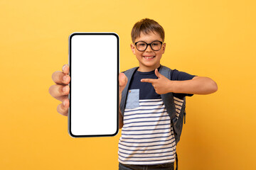 Happy schooler caucasian boy showing cell phone with blank screen