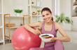 © Studio Romantic - Portrait of a young sporty slim woman wearing sportswear eating healthy food after working out at home. Fit girl with a bowl of fruits and berries. Healthy nutrition and lifestyle concept.