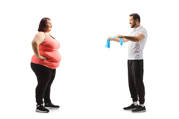 Canvas Print - Full length profile shot of a fitness trainer showing an exercise to an overweight young woman