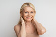 © Prostock-studio - Beauty portrait of mature woman adjusting long hair behind her ears, looking and smiling at camera, grey background