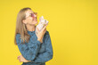 Profile portrait of a young adorable woman with sphynx cat profile on her hands isolated on yellow background