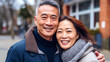 © Valua Vitaly - Portrait of happy asian couple looking at camera in the city. Portrait of smiling couple standing in street, lifestyle. Cheerful Western couple embracing each other. AI Generated.