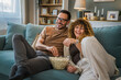 © Miljan Živković - Couple caucasian man and woman sit at home on sofa bed watch tv movie