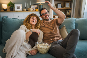 couple caucasian man and woman sit at home on sofa bed watch tv movie