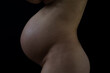 © Michael - Middle part of unrecognizable standing naked mother with round pregnant baby belly. Final month of pregnancy - week 36. Side view. Black background. Black an white.