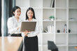 © Satori Studio - Two office workers talking with experienced colleague while using laptop computer in office, Colleagues discuss business, Business concept with copy space.