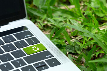 environmental technology concept.green recycle button on a black keyboard on green grass. Recycle zero waste ecology saving technology. Circular technology for digital and environmental sustainability