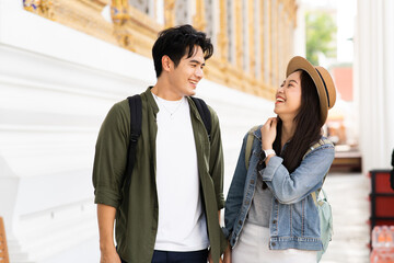 Wall Mural - Portrait of Asian man and woman travel couple backpackers in relationship inside of buddhist temple on the street in Bangkok, Thailand, Southeast Asia - carefree and happy traveling concept