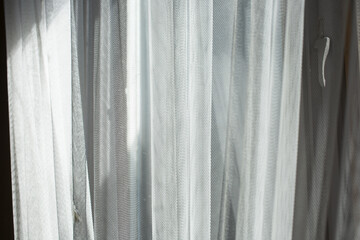 Wall Mural - A view of the sunlight glowing through a sheer curtain.