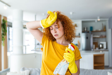 Portrait of young tired woman with rubber gloves resting after cleaning an apartment. Home, housekeeping concept.