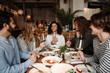 © Drobot Dean - Group of cheerful friends talking and drinking wine while dining in restaurant