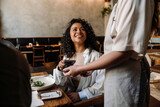 Fototapeta  - Woman using smartphone while paying restaurant bill with contactless payment during dinner party with friends
