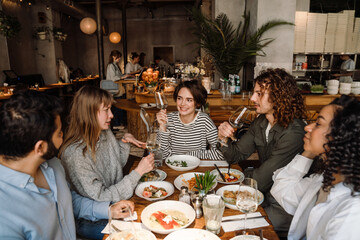 Group of friends drinking wine while dining in restaurant