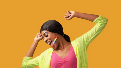 Happy dance. Fun joy. Positive lifestyle. Excited amused carefree smiling woman enjoying freedom luck isolated on bright orange color empty space background.